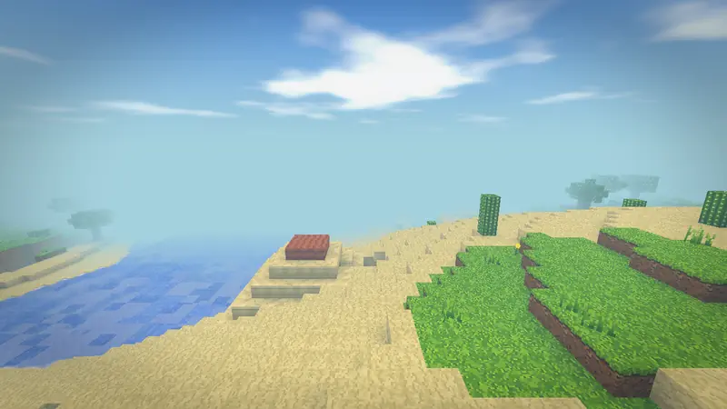 The edge of a desert in the middle lands: sand and cactus beside grassy terraces and the sea under a clear sky.